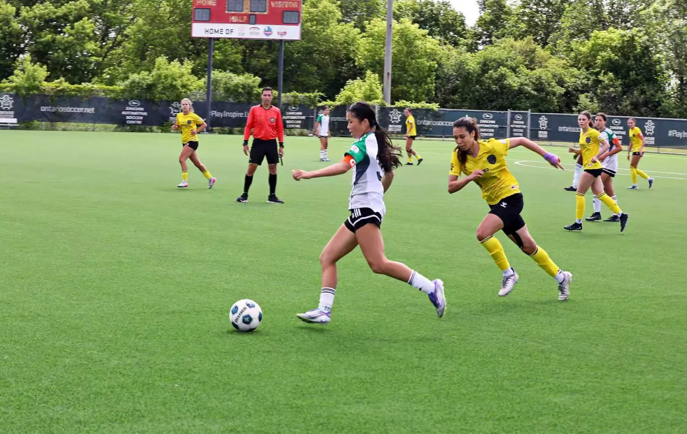 Angelina driving forward with the ball during a soccer match