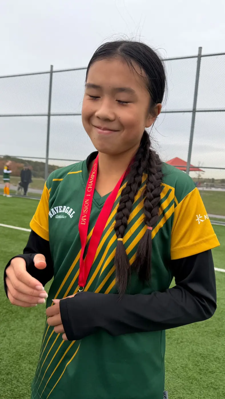 Angelina wearing her school soccer jersey and championship medal