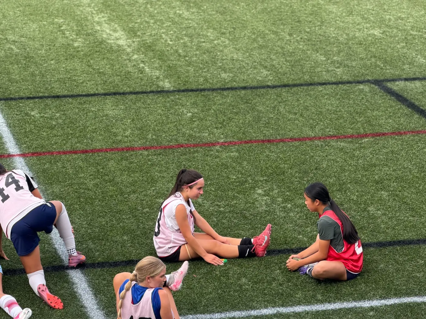 Angelina resting with other players beside the field